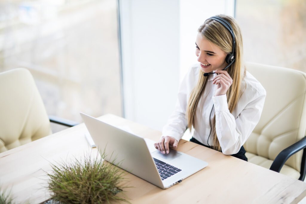 Portrait of happy smiling female customer support phone operator at workplace.