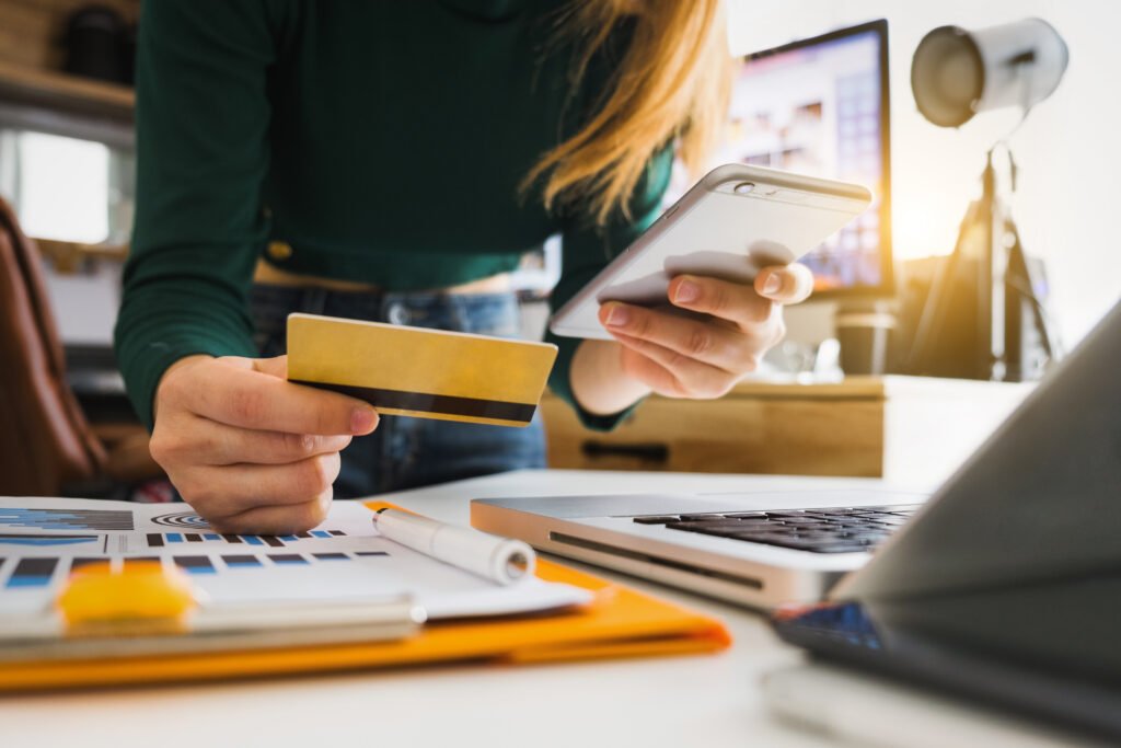 businesswoman hand using smart phone, tablet payments and holding credit card online shopping, omni channel, digital tablet docking keyboard computer at office in sun light