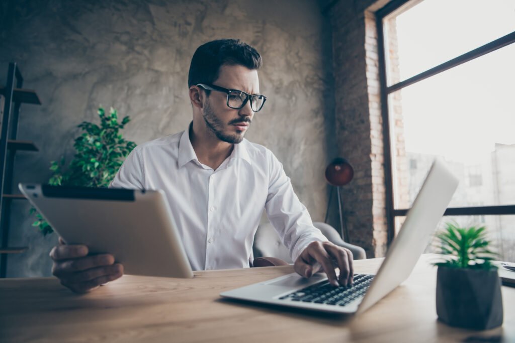 Portrait of his he nice attractive skilled experienced man employee creating financial report result economy start-up project IT at modern loft industrial style interior work place station