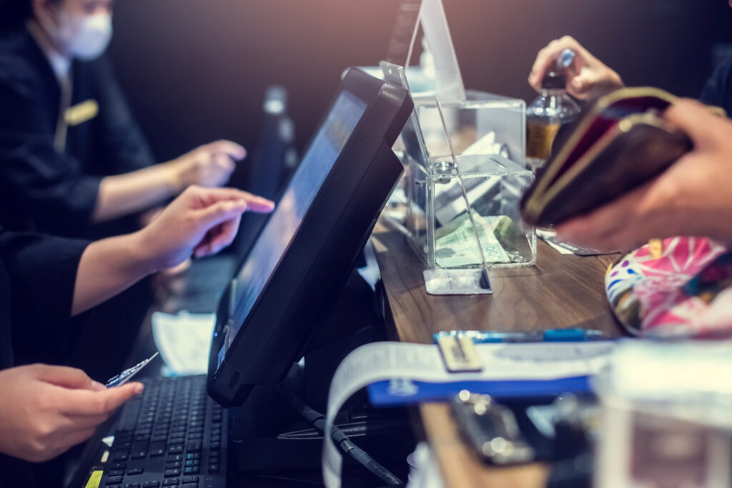 Selective focus to edge of POS machine with blurry cashier staff receive orders from customers at counter service in restaurant or cafe.